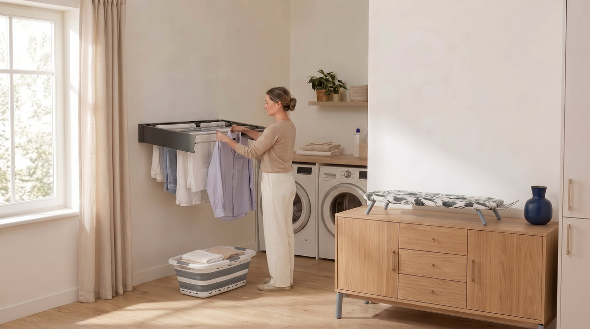 Waschküche am Waschtag: Wandwäscheständer ausgezogen, Wäschekorb am Boden, Tischbügelbrett auf dem Sideboard